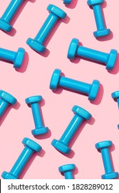 Fitness Dumbbells Blue On A Pink Background Pattern. Equipment For Home Workouts And Exercises In The Flat Lay Gym. Sports Dumbbell For A Healthy Lifestyle Top View.