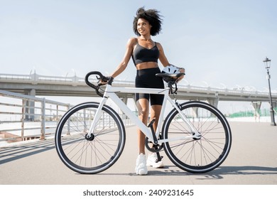 Fitness enthusiast pauses with her bike, showcasing a healthy lifestyle and urban cycling. - Powered by Shutterstock