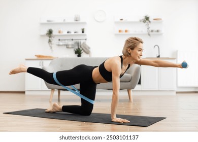 Fitness enthusiast performing yoga balance exercise on mat with resistance band in stylish home setting. Woman focused on core strength and stability in bright, cozy living space. - Powered by Shutterstock