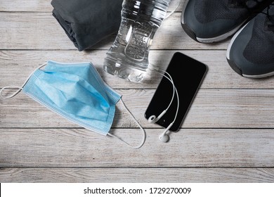 Fitness Equipment And Accessories On Wood Floor. Sneakers, Smartphone, Mask, 
Headphones , Water. Workout Concept