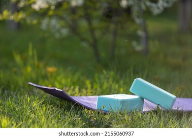 Fitness equipment on the green grass on a sunny day. yoga blocks on a yoga mat. Outdoors fitness concept. - Powered by Shutterstock