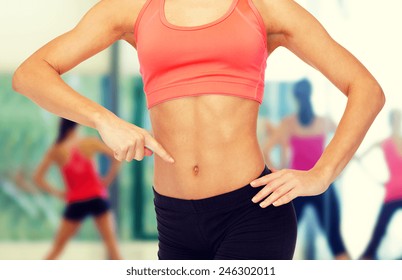 Fitness, Exercise And Diet Concept - Close Up Of Woman Pointing Finger At Her Six Pack