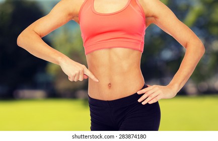 Fitness, Exercise And Diet Concept - Close Up Of Woman Pointing Finger At Her Six Pack