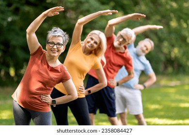 Fitness Exercises For Seniors. Sporty Mature People Training Together Outdoors, Group Of Happy Mature Men And Women Standing In A Row And Making Side Bend Workout, Enjoying Active Lifestyle - Powered by Shutterstock