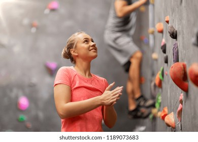Fitness, Extreme Sport And Healthy Lifestyle Concept - Young Man And Woman Bouldering On A Rock Climbing Wall At Indoor Gym