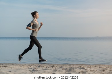 Fitness female doing running exercise on the beach. Sportswoman athlete jogging running in the morning in sportive clothes, shaping her body, doing physical exercises. - Powered by Shutterstock