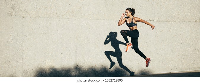 Fitness female model doing cardio exercise in morning. Panorama background of fitness woman running outdoors. - Powered by Shutterstock