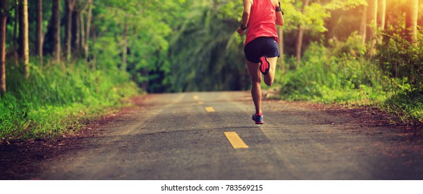 fitness female trail runner running in the forest 