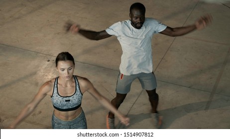 Fitness. Fit Couple Doing Jumping Jack Exercise At Gym Indoors. Young Healthy People Having Dynamic Warm Up Workout, Exercising Together At Sport Club