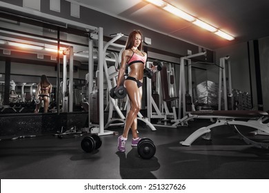 Fitness Girl Doing Exercise With Dumbbells In The Gym