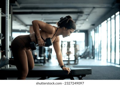 Fitness girl lifting dumbbell weights at the gym, doing exercises with dumbbell, fitness muscular body   - Powered by Shutterstock