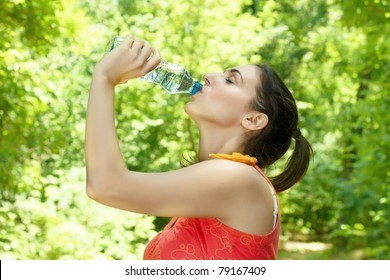 Fitness girl refreshing after exercising outdoors.