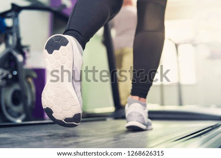 Fitness girl running on treadmill. Woman with muscular legs in modern gym. a girl in white sneakers running on a treadmill in the gym.