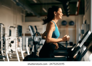 Fitness girl smiling and running on a treadmill, at the gym. - Powered by Shutterstock