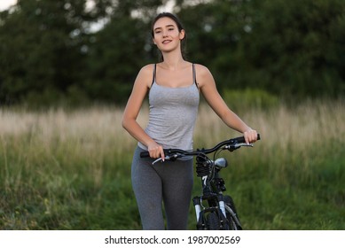 Fitness girl in sport clothes with bicycle. Healthy lifestyle concept. Summer woman portrait outdoor