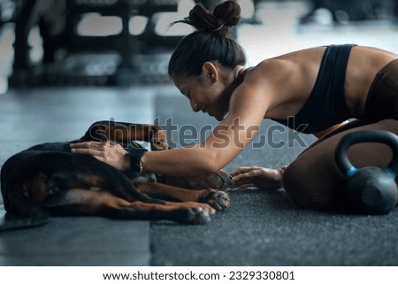 Fitness girl teasing and playing with her dog in the fitness gym, relationship between owner and pet 