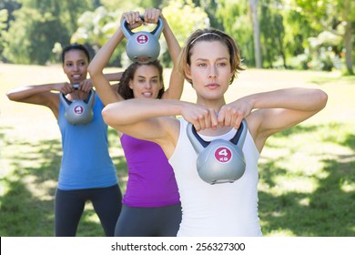 Fitness group working out in park with kettle bells on a sunny day - Powered by Shutterstock