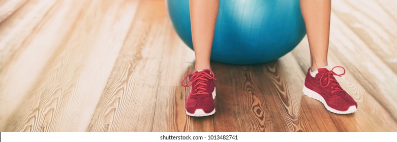 Fitness Gym Background Panoramic Banner With Copy Space On Floor. Closeup Of Running Shoes Of Fitness Woman Working Out On Exercise Ball In Gym Center. Sport And Health Panorama Crop.