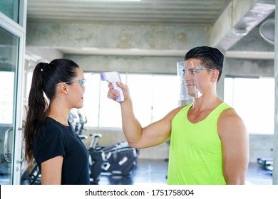 fitness gym protection virus.. trainer use an Infrared thermometer equipment to check the temperature on the forehead and use faceshild screen the patients addicted to Covid before entering the gym - Powered by Shutterstock