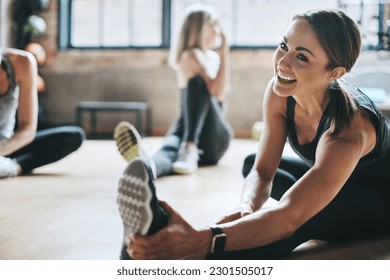 Fitness, gym and women stretching, exercise and workout goal for wellness, balance and stress relief. Female people, girls and athletes on the floor, stretch legs and smile with training and health