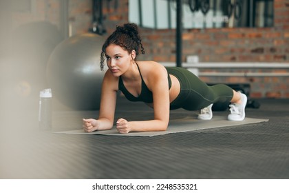 Fitness, gym and workout of a woman doing plank exercise or training for wellness with focus for healthy lifestyle. Female athlete with body weight routine for strong core, sports health and balance - Shutterstock ID 2248535321