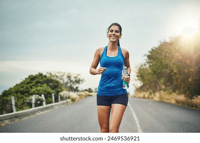 Fitness, happy woman and running with water bottle for exercise, cardio or wellness on road in nature. Female athlete, smile or workout on trail for health, sport or marathon training with sportswear - Powered by Shutterstock