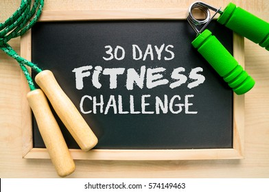 Fitness And Health Concept (30 Days Fitness Challenge). Skipping Rope, Hand Grip And Blackboard On A Wooden Table.