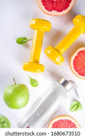 Fitness And Healthy Food Lifestyle Concept. Dumbbells, Diet Fruit And Vegetable Lunch Box, Water And Jump Rope On White Background. Flatlay Image, Top View Copy Space