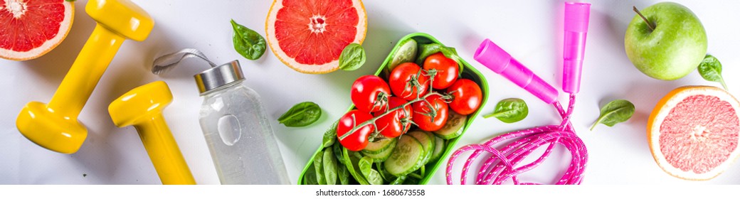 Fitness And Healthy Food Lifestyle Concept. Dumbbells, Diet Fruit And Vegetable Lunch Box, Water And Jump Rope On White Background. Flatlay Image, Top View Copy Space