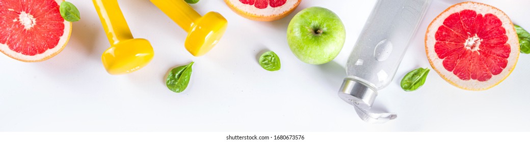 Fitness And Healthy Food Lifestyle Concept. Dumbbells, Diet Fruit And Vegetable Lunch Box, Water And Jump Rope On White Background. Flatlay Image, Top View Copy Space