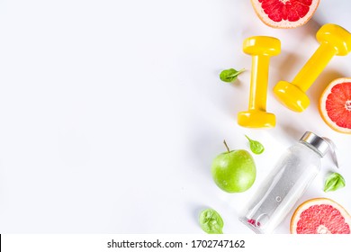 Fitness And Healthy Food Lifestyle Concept. Dumbbells, Diet Fruit And Vegetable Lunch Box, Water And Jump Rope On White Background. Flatlay Image, Top View Copy Space