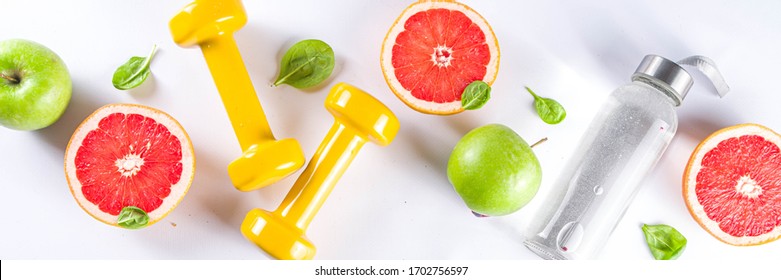 Fitness And Healthy Food Lifestyle Concept. Dumbbells, Diet Fruit And Vegetable Lunch Box, Water And Jump Rope On White Background. Flatlay Image, Top View Copy Space