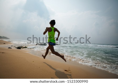 Fitness healthy lifestyle young woman running on tropical beach during sunrise in the morning
