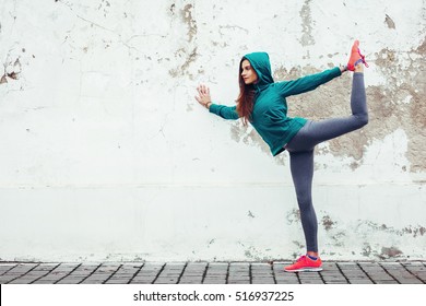 Fitness hipster girl in fashion sportswear doing yoga fitness exercise in the street, outdoor sports, urban style