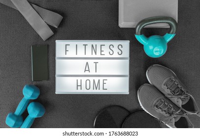 Fitness at home strength training program with dumbbells weights, resistance bands for cross fit workout on exercise mat .Top view of lightbox sign with black grey equipment.