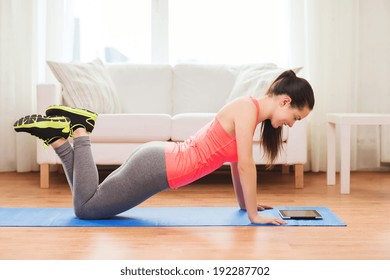 Fitness, Home, Technology And Diet Concept - Smiling Teenage Girl Doing Push-ups And Looking At Tablet Pc Computer At Home