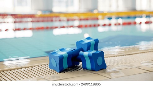 Fitness, indoor sport or dumbbell at swimming pool for safety, learning or aqua aerobics. Blue equipment, water or sponge weights at poolside for muscle therapy, growth or float in wellness center - Powered by Shutterstock