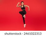 A fitness instructor is captured mid-motion while performing a high-knee exercise, showcasing her strength and agility. She is dressed in athletic wear and appears focused and determined