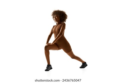 Fitness instructor demonstrating lunge training in brown activewear against white studio white background. Exercises for legs. Concept of sport, mourning routine, active and healthy lifestyle, action.