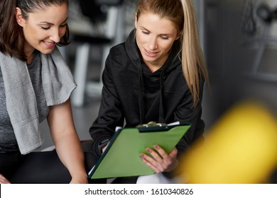 Fitness Instructor And Young Woman Talking At Gym 