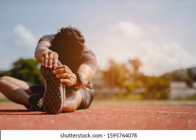 fitness, jogging, running, exercise, lifestyle and healthy concept. The young man wore all parts of his body to prepare for jogging on the running track around the football field. - Shutterstock ID 1595764078