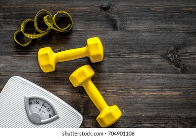 Fitness For Losing Weight. Bathroom Scale, Measuring Tape And Dumbbell On Wooden Background Top View Copyspace