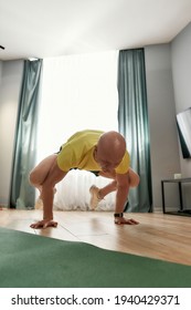 Fitness Male Coach Looking Focused While Standing On His Arms And Legs In The Air, Exercising In Living Room At Home. Hard Yoga Pose. Fitness, Healthy Lifestyle, Stay Home Concept