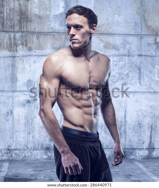 fitness male model\
in old garage rusted\
walls