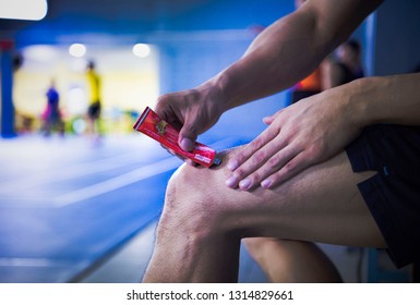 A Fitness Man Applying Ointment Cream (lotion) Onto His Knee To Relieve The Pain Or Injury