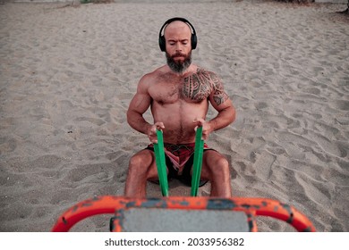 Fitness Man Doing Calisthenics Workout With A Resistance Band At The Beach.