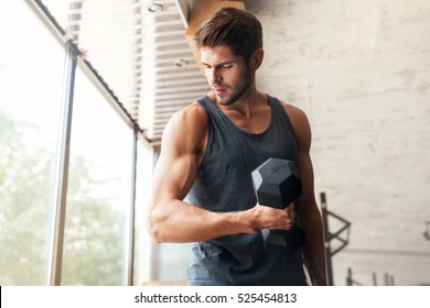 Fitness Man With Dumbbell In Gym. Looking Away