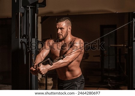 Fitness man execute exercise with exercise-machine Cable Crossover in gym. Handsome man with big muscles in gym. Machine in the gym.