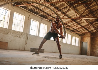 Fitness man exercising with battle rope in abandoned warehouse. Strong man exercising in  training gym made inside old factory. - Powered by Shutterstock