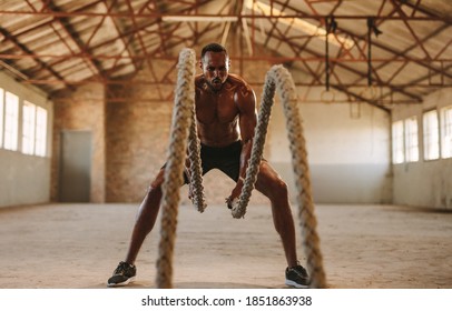 Fitness Man Exercising With Battling Rope In Training Gym Inside Old Warehouse. Muscular Man Working Out At Empty Warehouse.